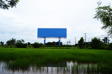 The blue billboards at field and electric post with sky near the roadの写真素材