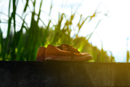 old brown shoes with sun light on cement wall in eveningの写真素材
