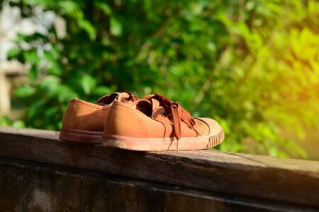 old brown shoes with sun light at  wood on cement wallの写真素材
