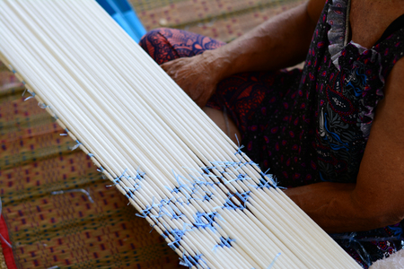 an old woman makes the pattern of the fiber before take to weavingの写真素材
