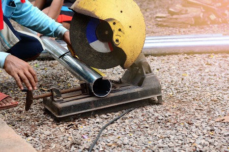 a man using a steel cutter machine on construction site groundの写真素材