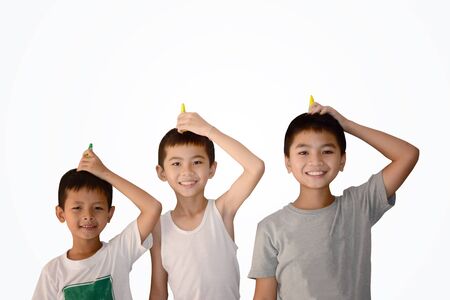 3 young asian boys playing christmas poppers on their head with white background isolated