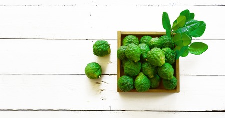 stack of fresh green bergamot with young leaves in wood box on white table and old brown wood backgroundの写真素材