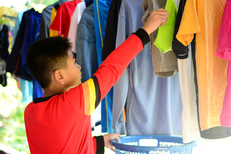 the  asian boy doing housework by hanging clothes with clothbarの写真素材