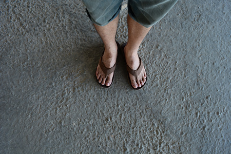 the rough and dirty old ground with the legs of a man wear brown sandalの写真素材