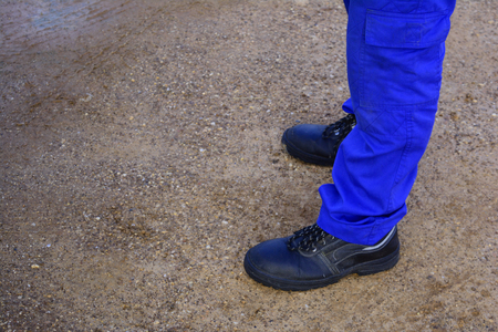 a man with black safety shoes standing on the wet  street and full of mud at the country of thailandの写真素材