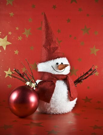 toy snowman in a red cap with a red backgroundの写真素材