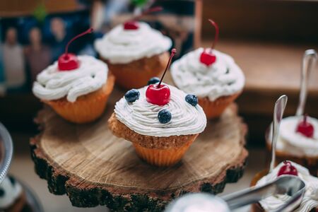 Cupcakes with cherrie and blueberries on wooden stand, selective focusの写真素材