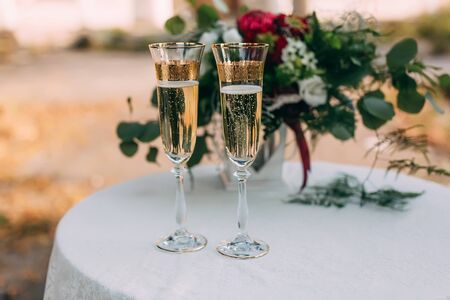 Two glasses of champagne at wedding decorated table with bouquet of flowersの写真素材