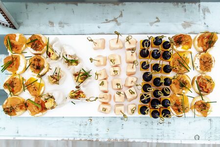Different light snack on wooden tray on wedding partyの写真素材