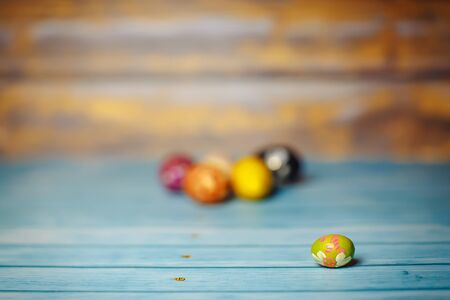 Easter colored painted small egg on blue and brown blurry wooden background with copyspaceの写真素材