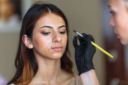 Beautiful model in make up process. Portrait of young pretty woman with beutiful makeup in beauty...