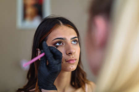 Beautiful model in make up process. Portrait of young pretty woman with beutiful makeup in beauty studio salon. Evening make up, blurry backgroundの写真素材