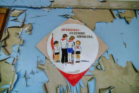 Concrete Texture old wall with peeling paint with picture on it with the inscription Octobrists - the future pioneers in Abandoned school of ghost town Pripyat Chornobyl Zone.の写真素材