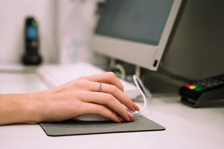 Close up hand of young woman administrator works at the reception of fitness club or health centre. Working on computer.の写真素材