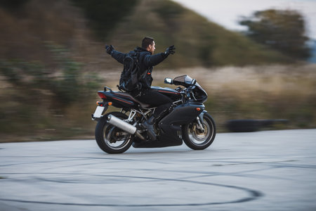 Young biker riding a sport motorbike without hands and feel free. Freedom concept. Motion blur on background.の写真素材