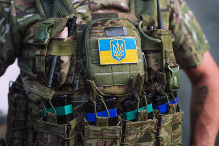 Close-up of a Ukrainian soldier tactical vest with Ukrainian flag and trident emblem patch. Military...