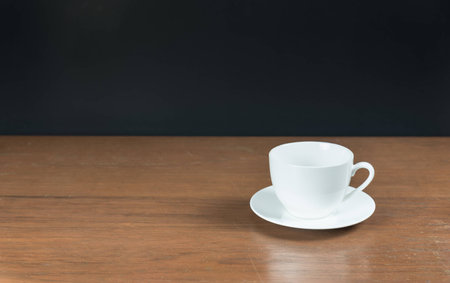 empty white cup of coffee on the wood table with black background photograph by front viewの写真素材