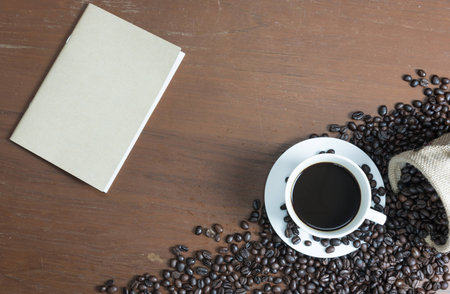 white cup of coffee on the wood table with coffee bean and notebook photograph by top viewの写真素材