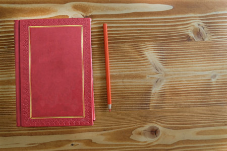 antique red gilded book on the old wood table with colorful pencils for distance learningの写真素材
