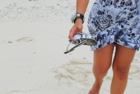 Summer in the sand A woman walks in the sand with sandals in her handの写真素材