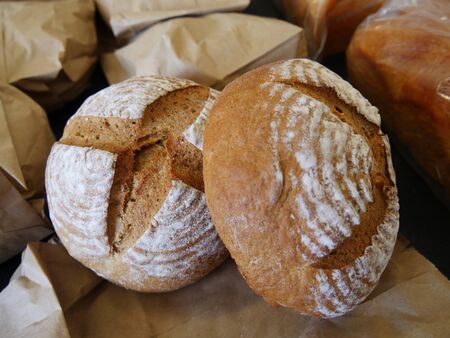 Homemade hard round wheat bread displayed with paper bags in the background