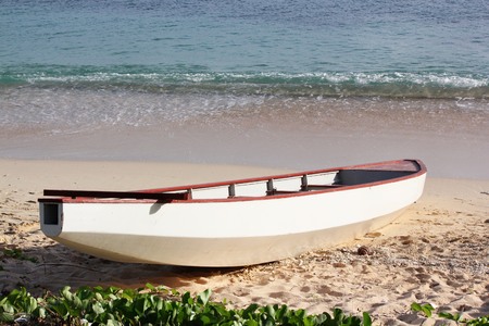 Small white boat docked in the sand in a tropical beachの写真素材