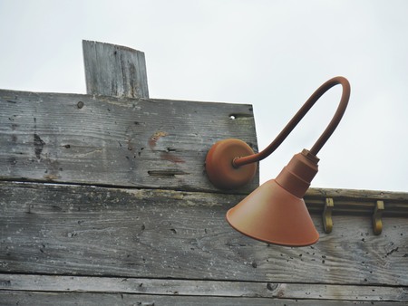 Antique wall lamp mounted on a wooden wall outdoorsの写真素材