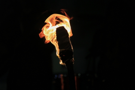 Fire burning from a flaming tiki torch against a dark backgroundの写真素材
