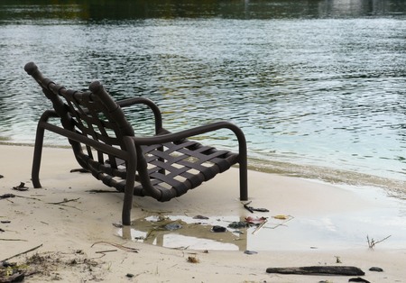 Dark brown chair with legs half-sunk in the white sand beachの写真素材