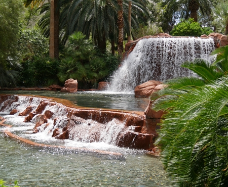Water cascades down two tiers of waterfalls from a landscaped gardenの写真素材
