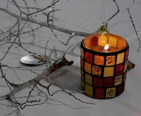 A candle burning inside a colorful artistically designed glassの写真素材