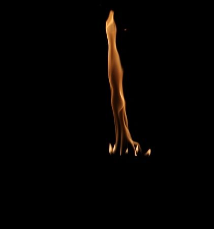 Flames from a burning torch rising straight up with smaller flames at its base, against a dark backgroundの写真素材