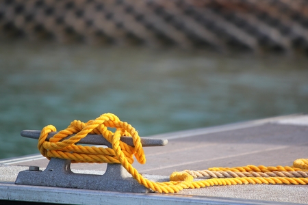 Piece of new yellow rope tied to a moor waiting for a boat to tied to the dockの写真素材