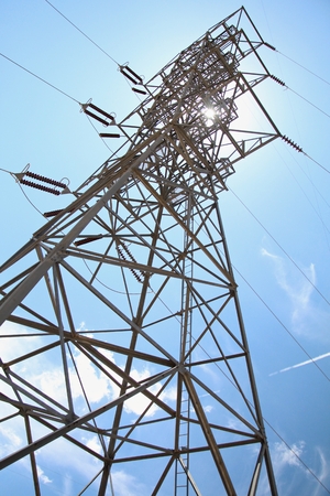A high voltage power line  with the streak of the sun peeking through on a bright sunny dayの写真素材