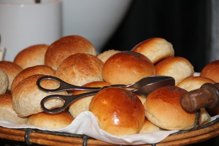 Assorted freshly baked bread in a wicker tray, with silver tongsの写真素材