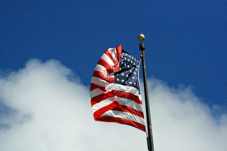 A flag of the United States of America flying folded in the windの写真素材