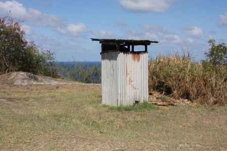 An outhouse made of rusting tin roof in the jungle beside the bushesの写真素材