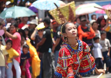 Davao City, Philippines-August 2014: Focused shot of a girl in colorful costume with the crowd blurred on the streetside. Kadayawan is celebrated August each year to give thanks for life and an abundant harvest.のeditorial素材
