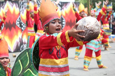 Davao City, Philippines-August 2014: Medium close up of a street dancer offering a grown coconut at the Kadayawan festival. Kadayawan is celebrated August each year to give thanks for life and an abundant harvest.のeditorial素材