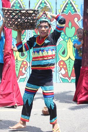 Davao City, Philippines-August 2014: A parade participant carries a basket of coconuts for their...