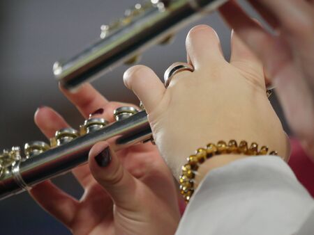 Hands of band members playing notes on a flute, close up
