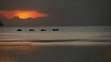 Silhouette of jetskis in the water with warm sunset colors in the water 