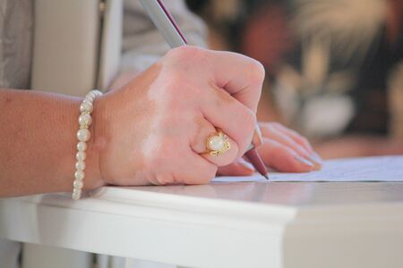 Hand of a female wedding sponsor signing the marriage contract