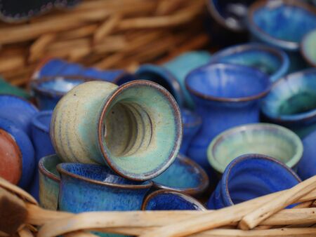 Colorful blue handmade ceramic mugs displayed for sale at a festivalの写真素材