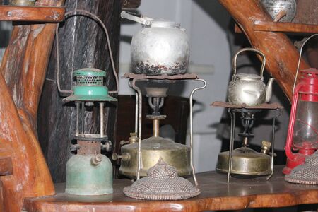 A collection of vintage oil lamps and gas burners displayed in a century-old house. 