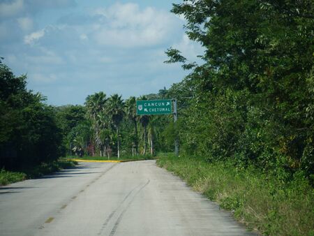 Paved road and intersection with directional signs to Cancun and Chetumal, Mexico.の写真素材