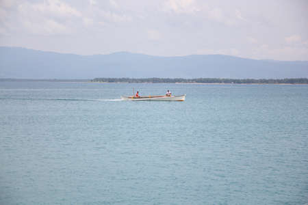 Surigao del Sur, Philippines- August 2014:  Wide shot of the bay with two men on a boat fishing in Cantilan, Surigao del Sur.のeditorial素材