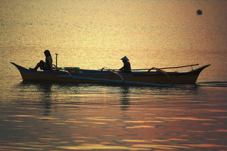 Surigao del Sur, Philippines- August 2014: Fishermen set out in an outrigger boat at sunrise in...