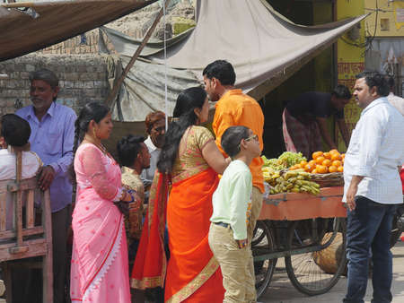 Mathura, Uttar Pradesh, India- March 2018: People check out a sidewalk cart selling fresh fruits from a vendor in Mathura.のeditorial素材